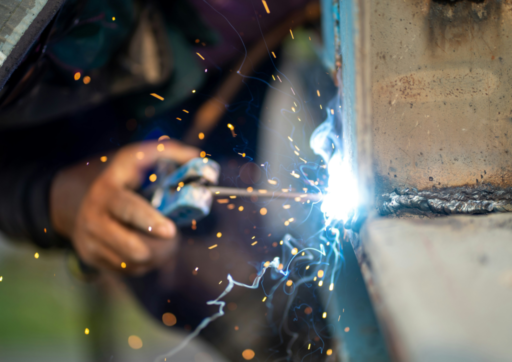 Sudor profesionist lucrând la realizarea unei imbinari cu echipament de protecție